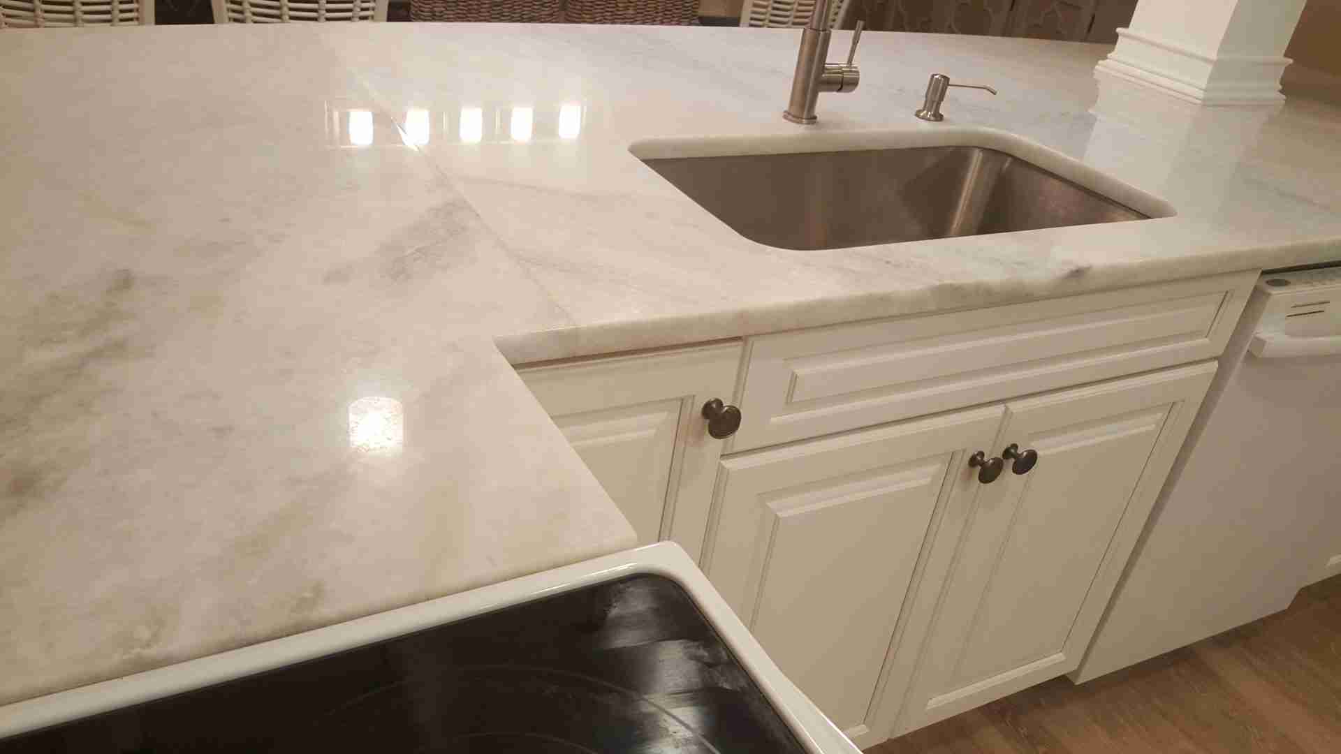 Photo of White and Gray Marble Countertops in a Residential Kitchen with Lights Reflecting off the Glass-like Surface After Professional Marble Cleaning and Polishing by Bay Shore Cleaning & Restoration Bay Shore Cleaning & Restoration