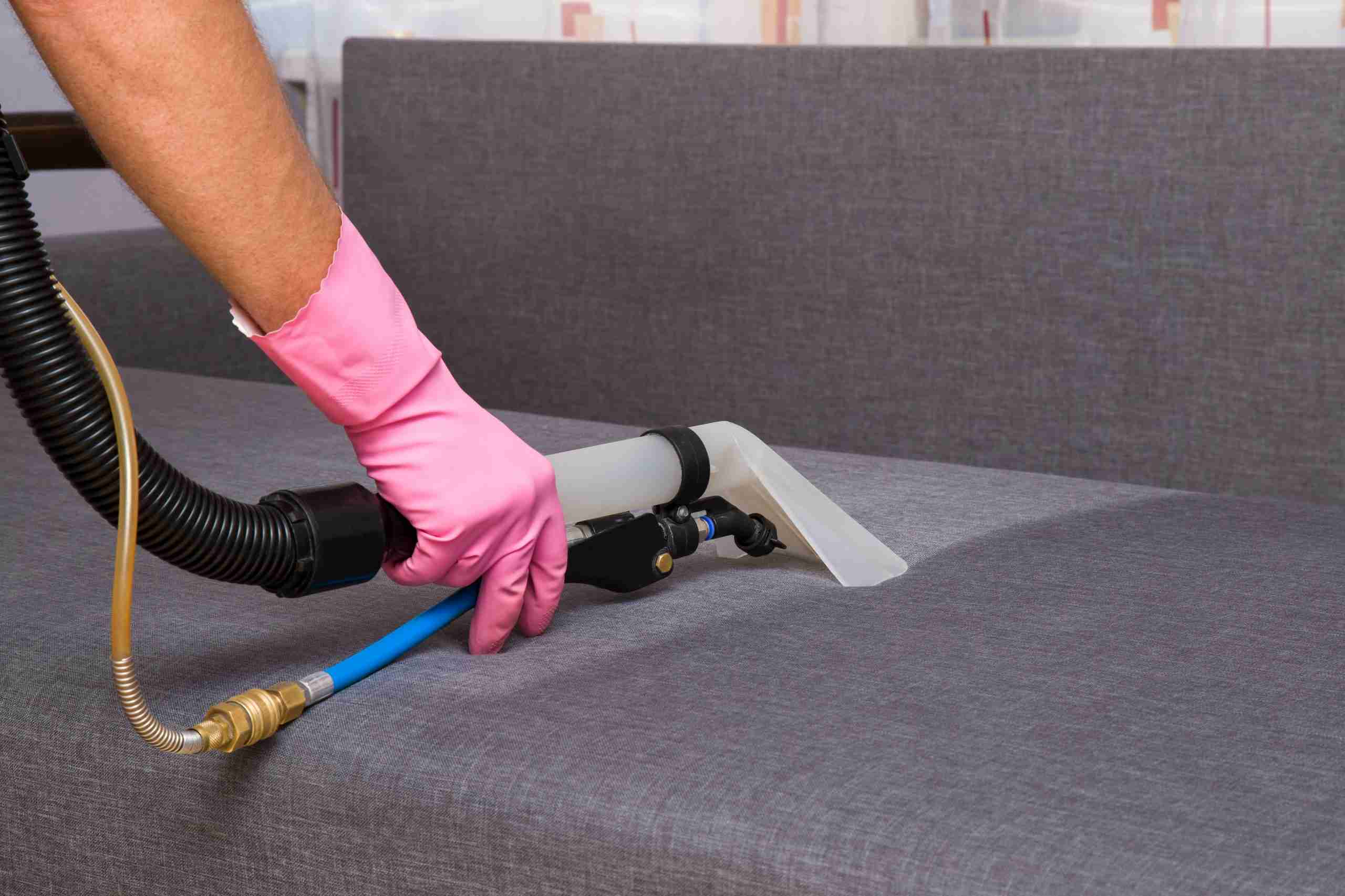Close Up Photo of a Technician's Hand Using a Steam Cleaner to Professionally Clean an Upholstered Couch Bay Shore Cleaning & Restoration